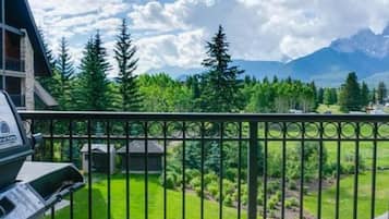 A mountain cabin with a balcony overlooking a lush green landscape and distant mountains.