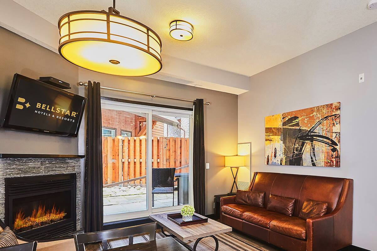 A living room with a fireplace, a leather sofa, a coffee table, and a TV mounted on the wall.