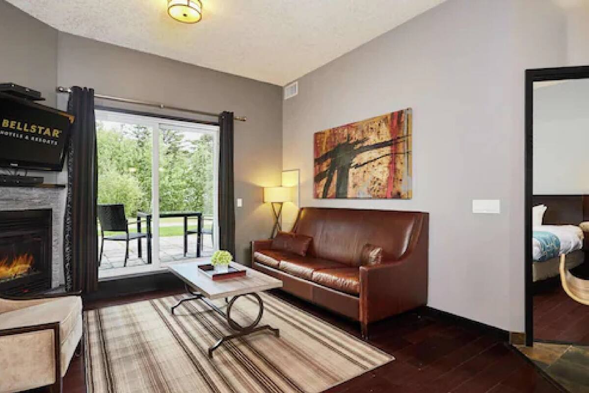 A living room with a fireplace, a leather sofa, a coffee table, and a painting on the wall.