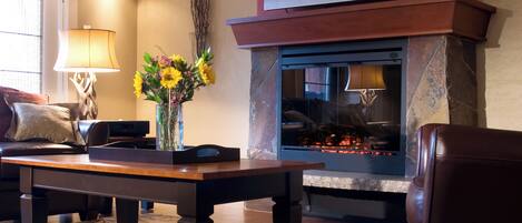 A living room with a fireplace, a television mounted above it, a coffee table, and a sofa.