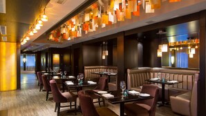 A restaurant with booths and tables, each set with plates, glasses, and cutlery. - Grande Rockies Resort - Bellstar Hotels & Resorts (Canmore)