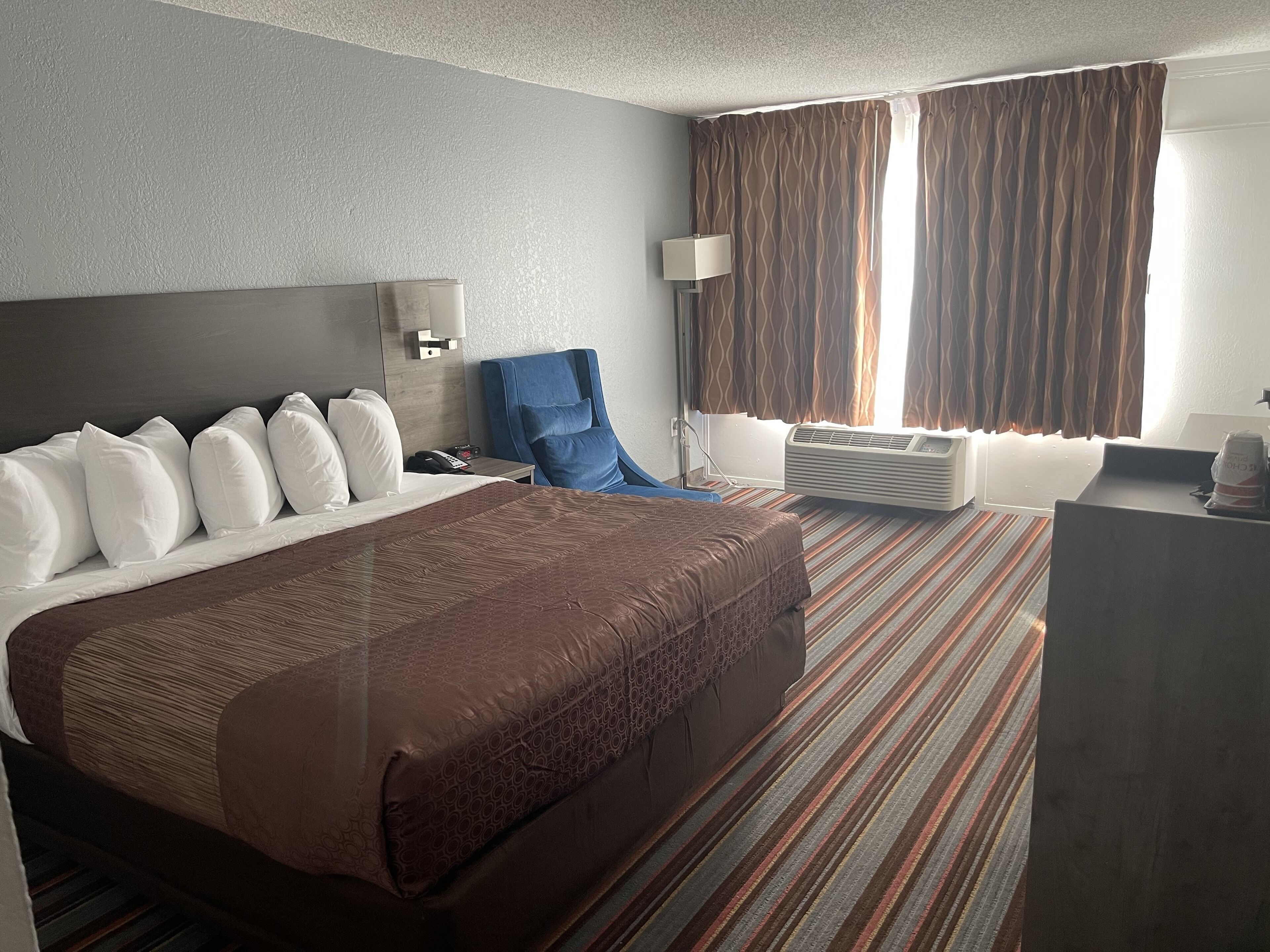 Een hotelkamer met een groot bed, een bureau, een stoel en een raam met gordijnen.