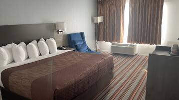Een hotelkamer met een groot bed, een bureau, een stoel en een raam met gordijnen.