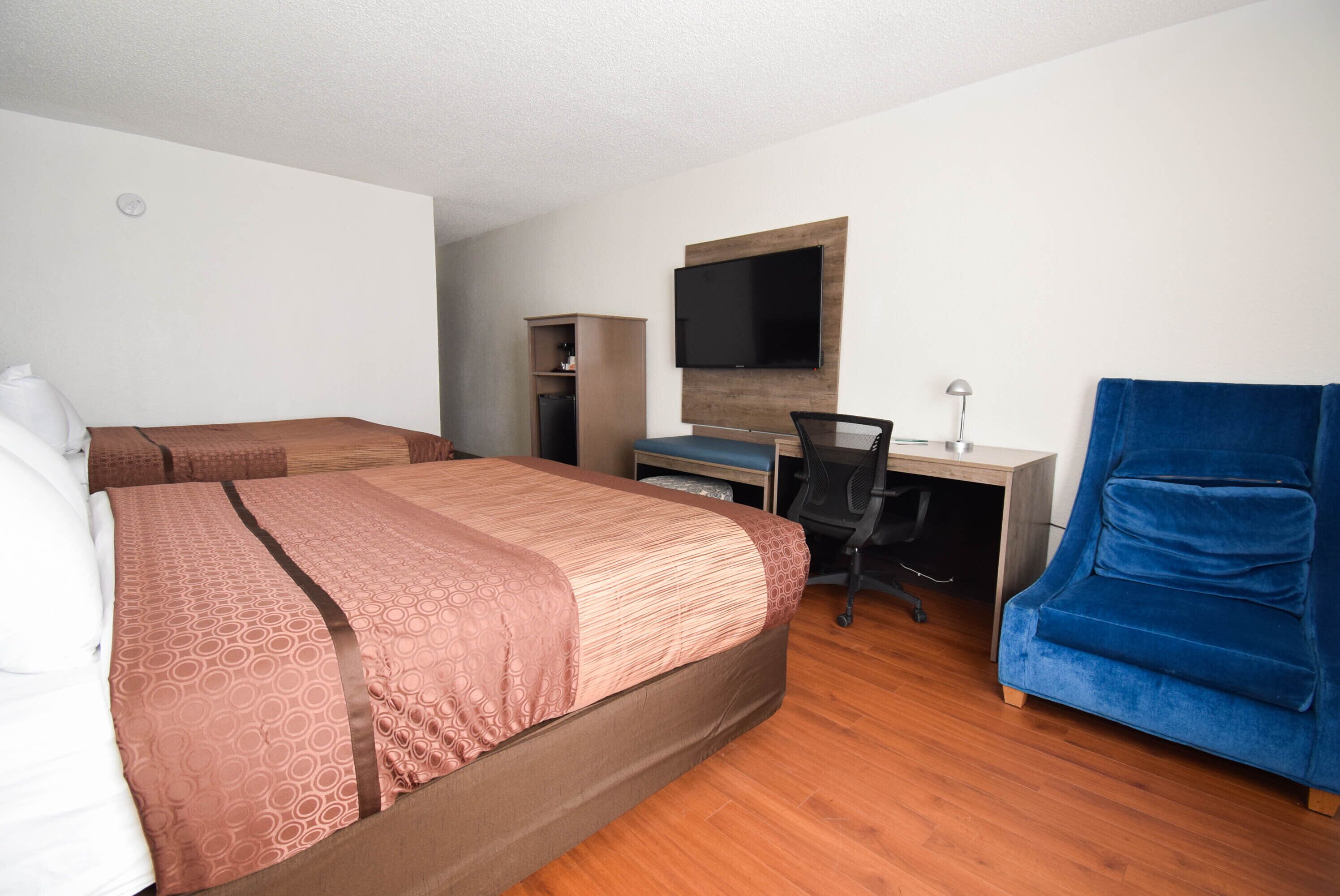 Una habitación de hotel con una cama, un escritorio, una silla, un televisor y un armario.