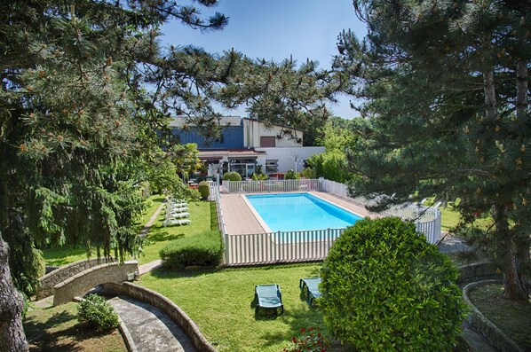 A swimming pool surrounded by a white fence, a stone bridge, and a stone wall.