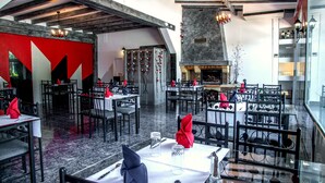 A restaurant with high ceilings, exposed beams, and a central fireplace. Tables are set with red napkins and clear glassware. - Relais 500 de Vienne (Chonas-l'Amballan)