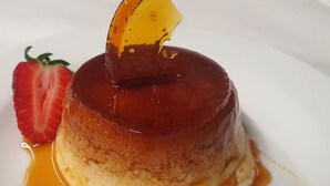 A caramel flan on a white plate with a strawberry and a caramelized orange slice on top. - Relais 500 de Vienne (Chonas-l'Amballan)