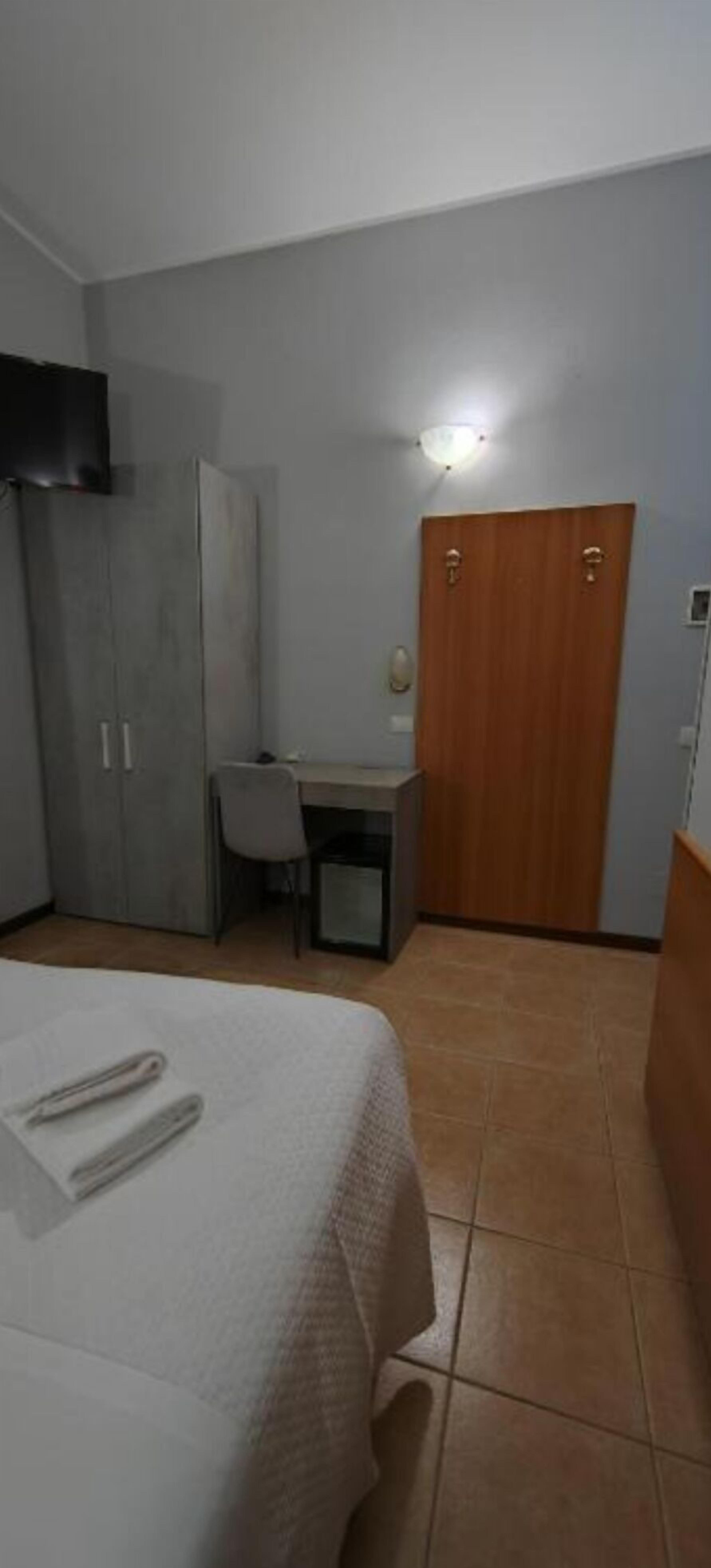 Ein Hotelzimmer mit Bett, Schreibtisch, Stuhl und Kleiderschrank.