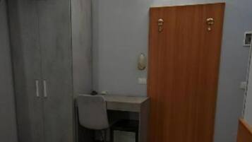 Ein Hotelzimmer mit Bett, Schreibtisch, Stuhl und Kleiderschrank.