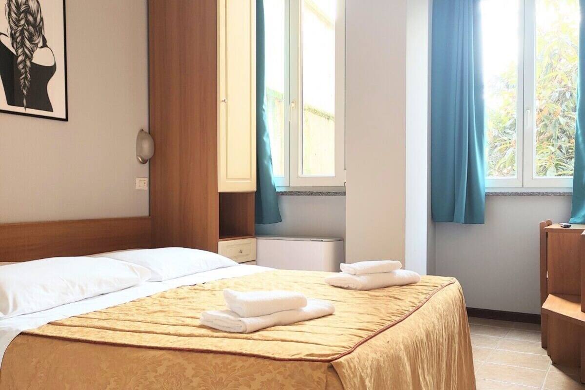 A hotel room with a bed, a wardrobe, a bathroom, and a window with curtains.