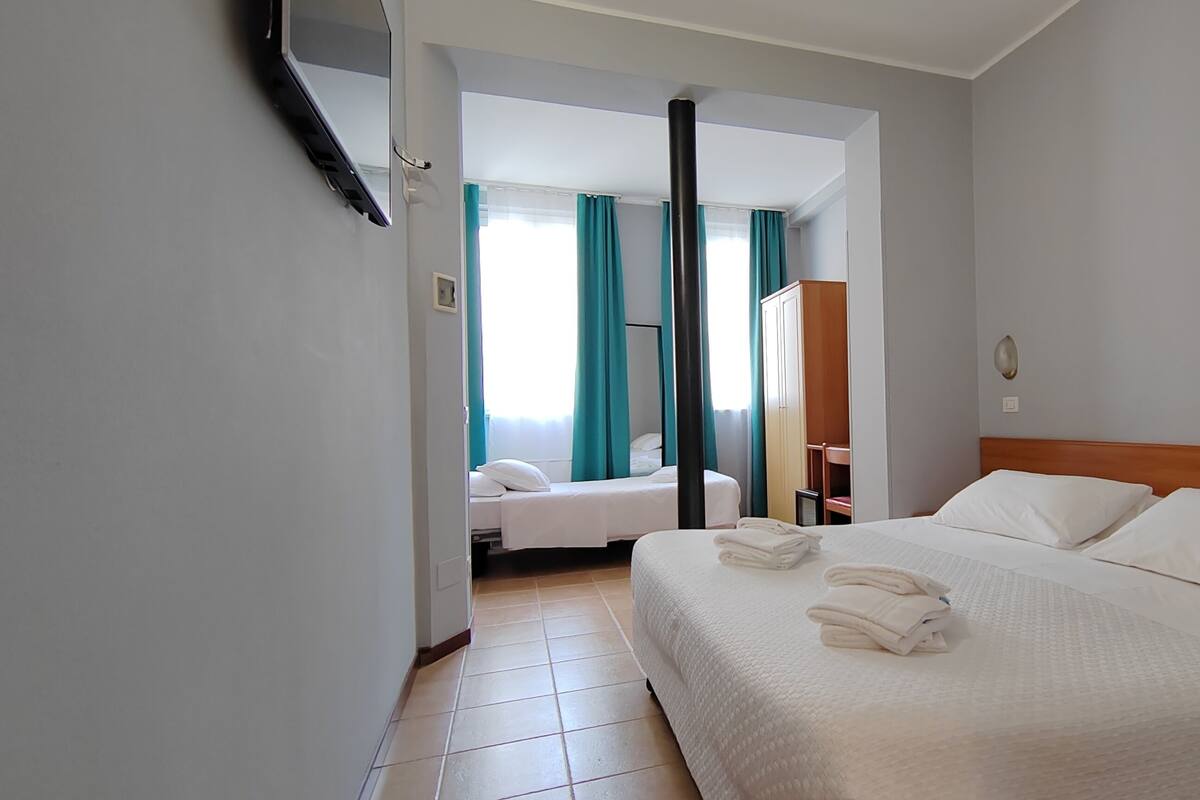 A hotel room with a large bed, a smaller bed, and a bathroom visible through an open door.