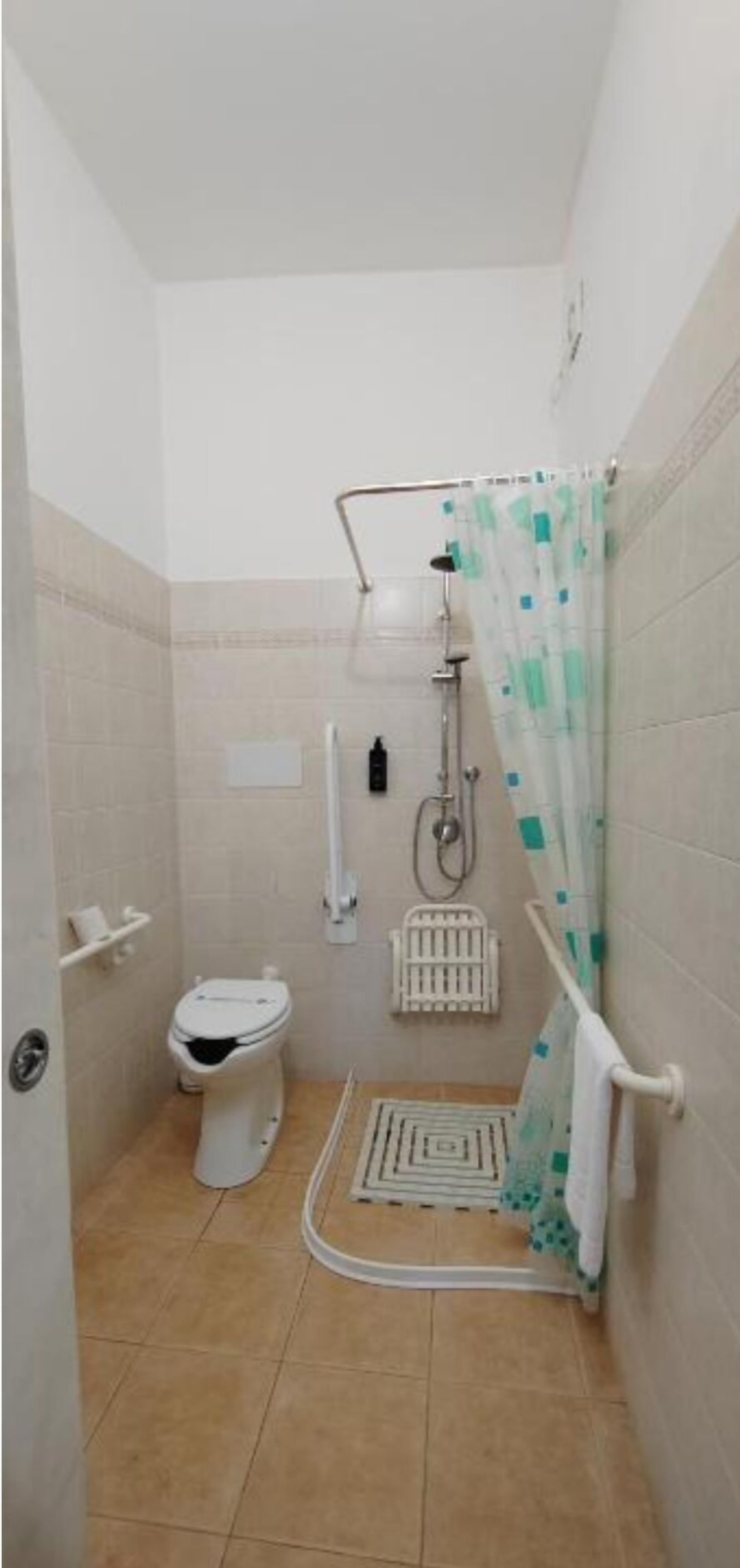 Un baño pequeño y cerrado con inodoro, ducha y un perchero para toallas.