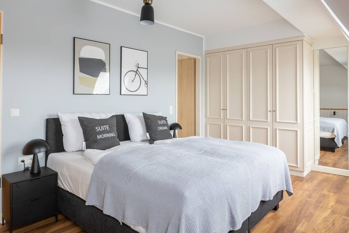 Un dormitorio moderno con una cama grande, una mesita de noche, un armario y una lámpara en el techo.