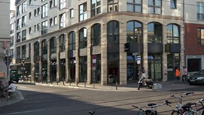 Un edificio de varios pisos con amplios ventanales y una entrada en esquina.