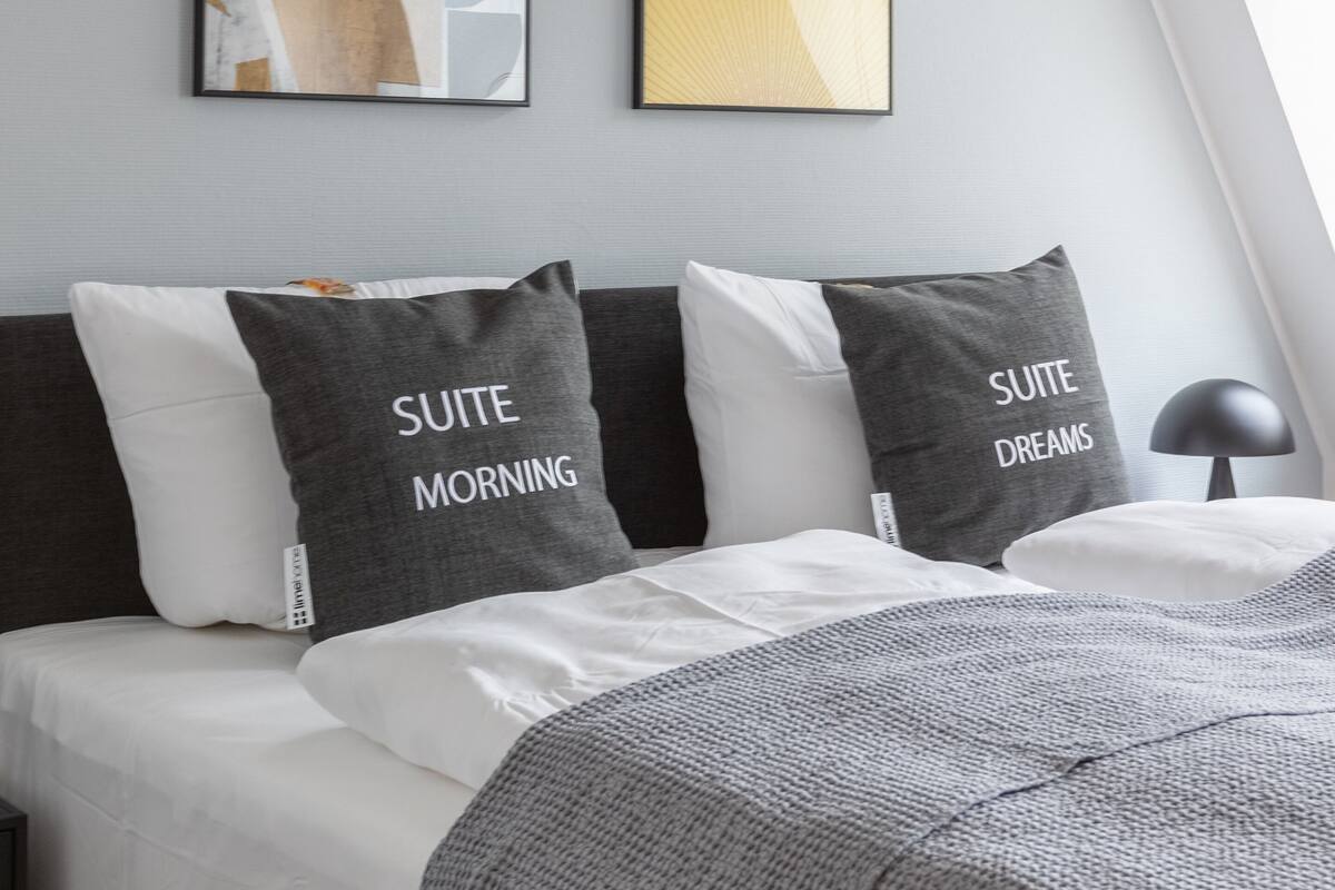 Un dormitorio moderno con una cama, dos almohadas y dos obras de arte en la pared.