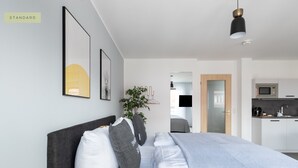 Un dormitorio moderno con una cama grande, un cabecero oscuro y una lámpara colgante.