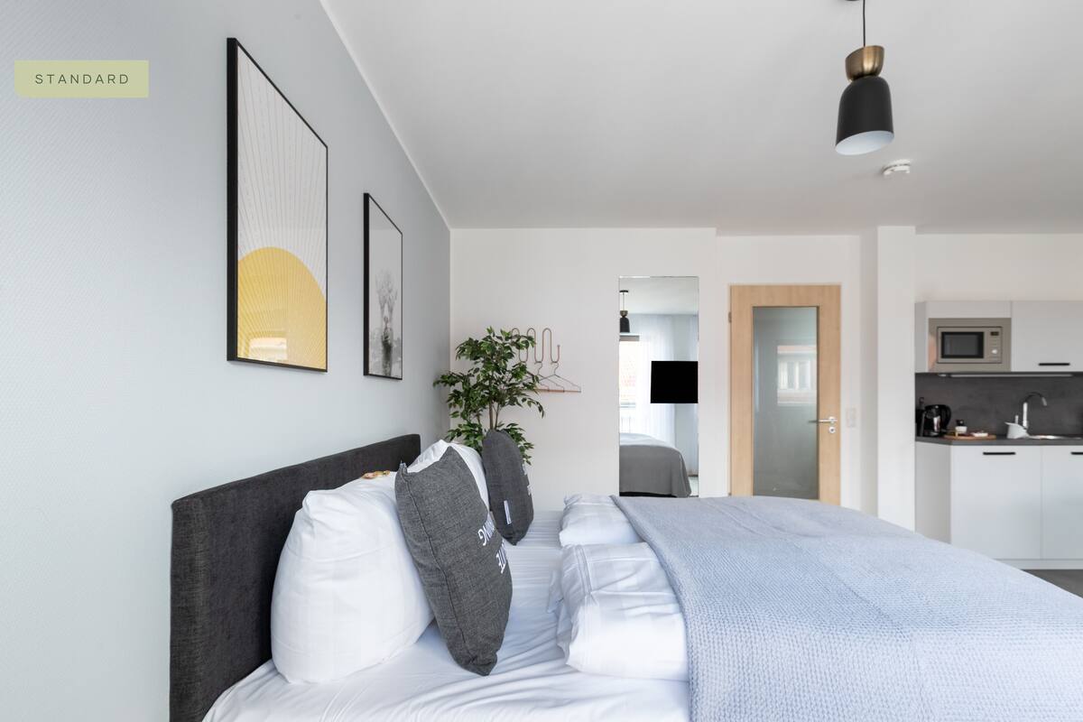 Un dormitorio moderno con una cama grande, un cabecero oscuro y una lámpara colgante.