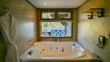 Un bagno con una grande vasca da bagno, una finestra con vista su un balcone e un telefono fissato al muro.