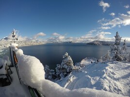 Un paisaje nevado con un lago, montañas y una terraza de madera.