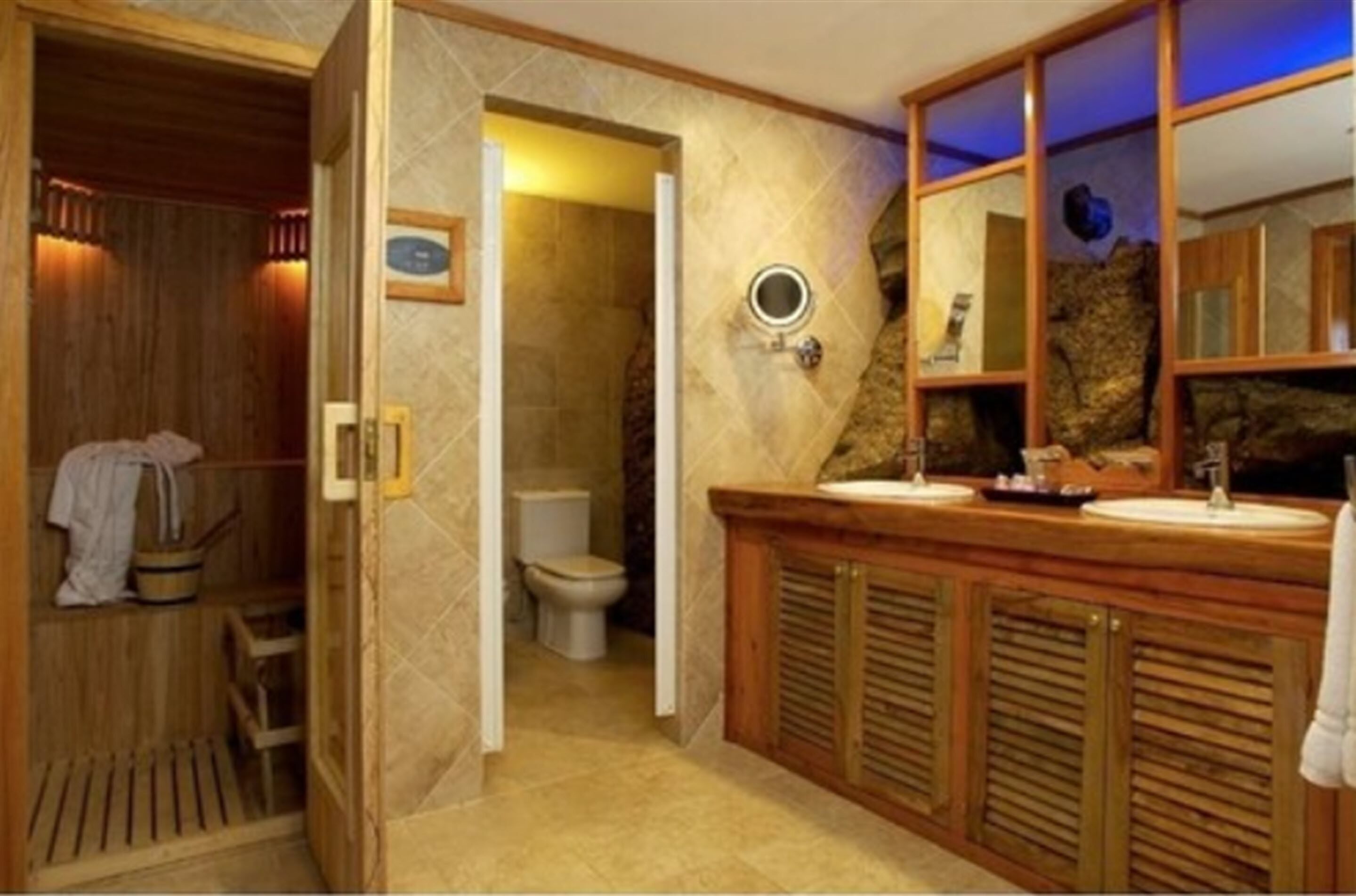 Un baño con sauna de madera, tocador de madera con espejo y un inodoro.
