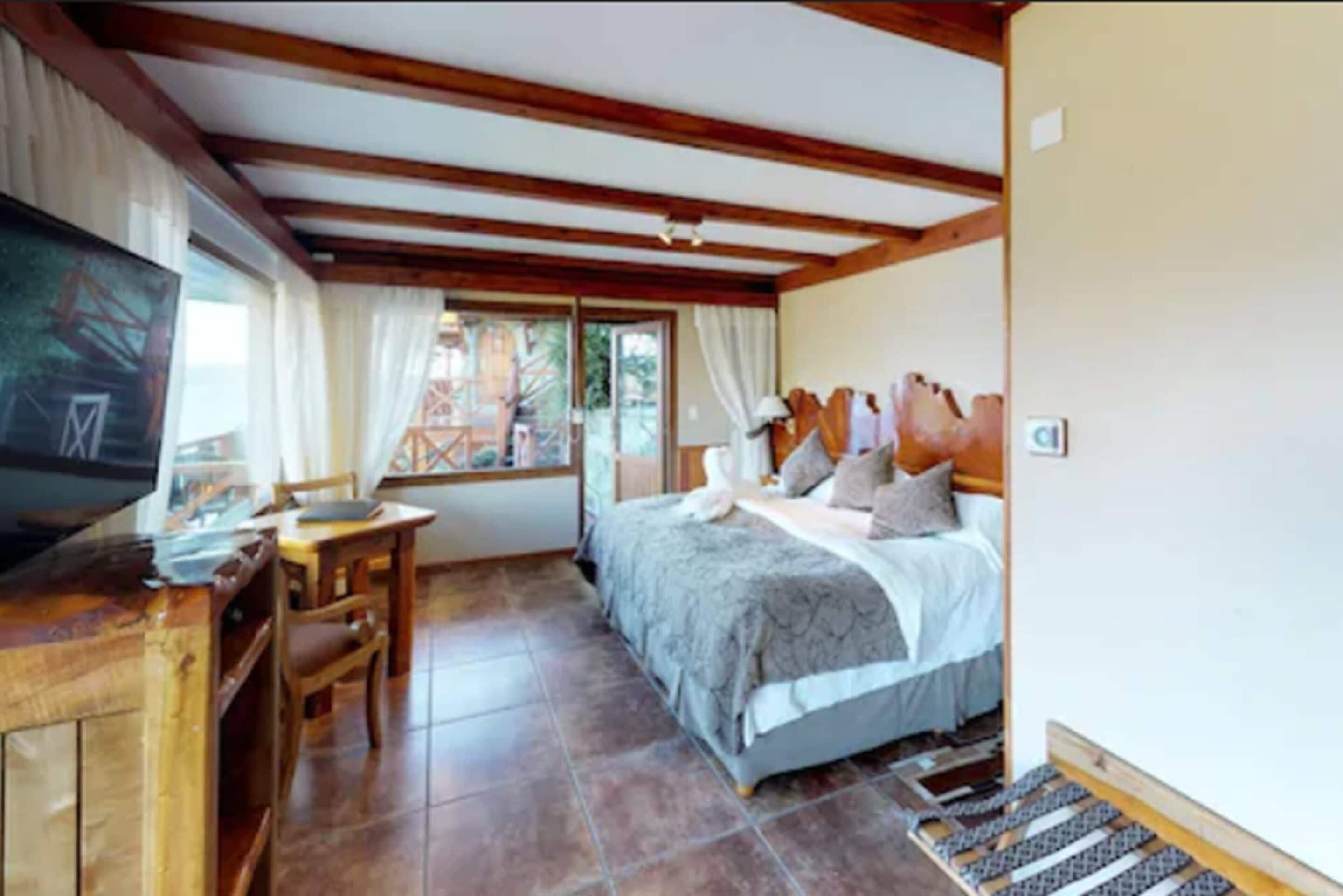 A bedroom with a bed, a desk, and a window.