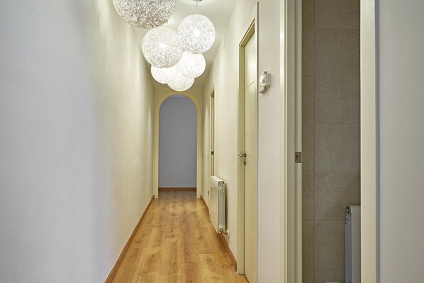 A hallway with wooden flooring, white walls, and a radiator on the right.