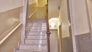 Eine Treppe mit Granitstufen und einem Holnänder, die zu einem Aufzug führt.