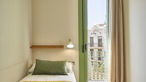 Ein Hotelzimmer mit Bett, Nachttisch, Lampe und Blick auf den Balkon.