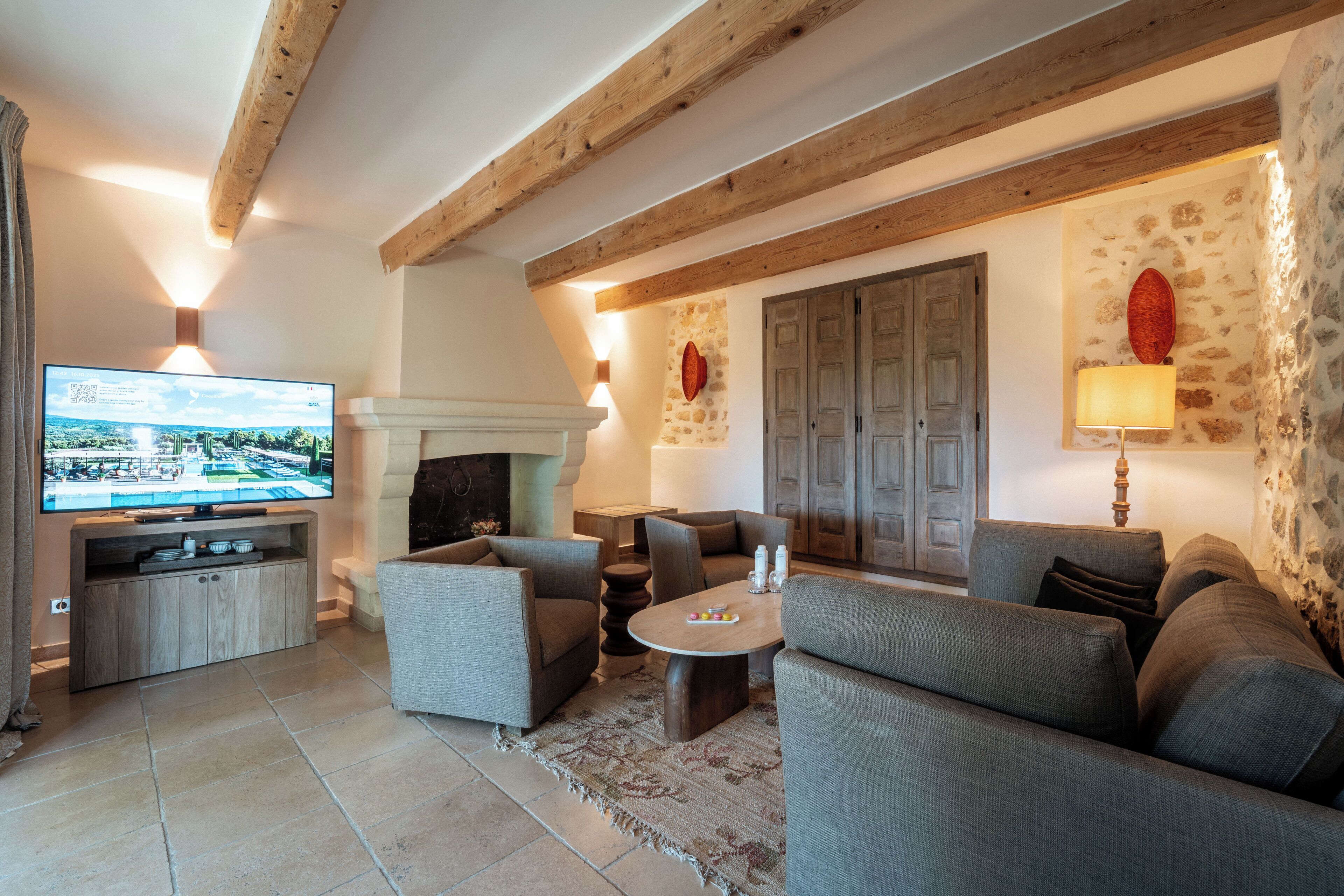 Una sala de estar con chimenea, sofás, televisor y paredes de piedra.
