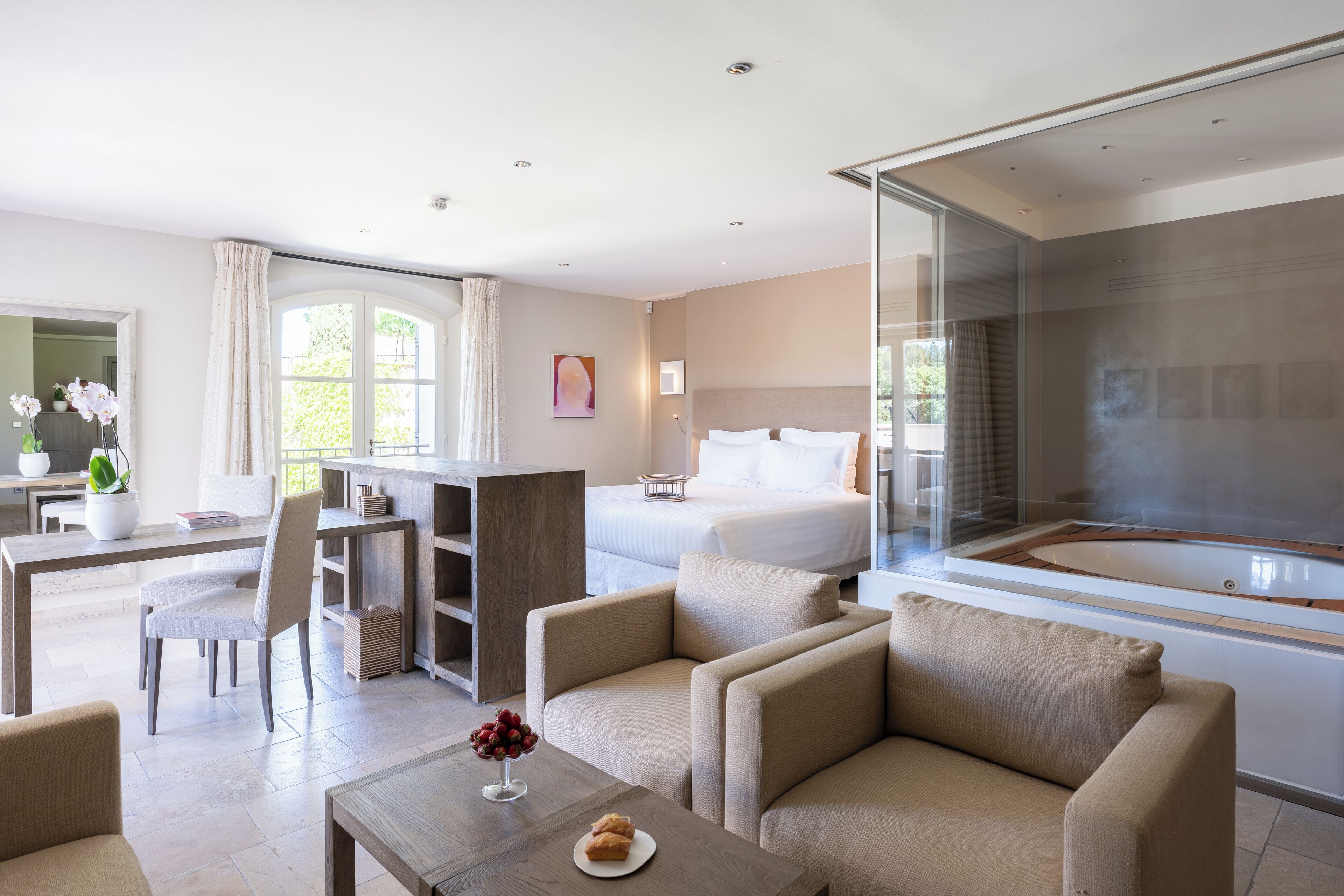 Une chambre d’hôtel moderne comprenant un lit, un coin salon avec des canapés, une table à manger et une grande fenêtre.