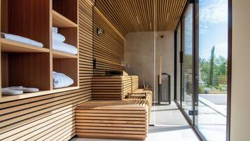 Un spa moderno con paredes de listones de madera, una zona de estar con bancos y vistas al exterior a través de grandes ventanales.