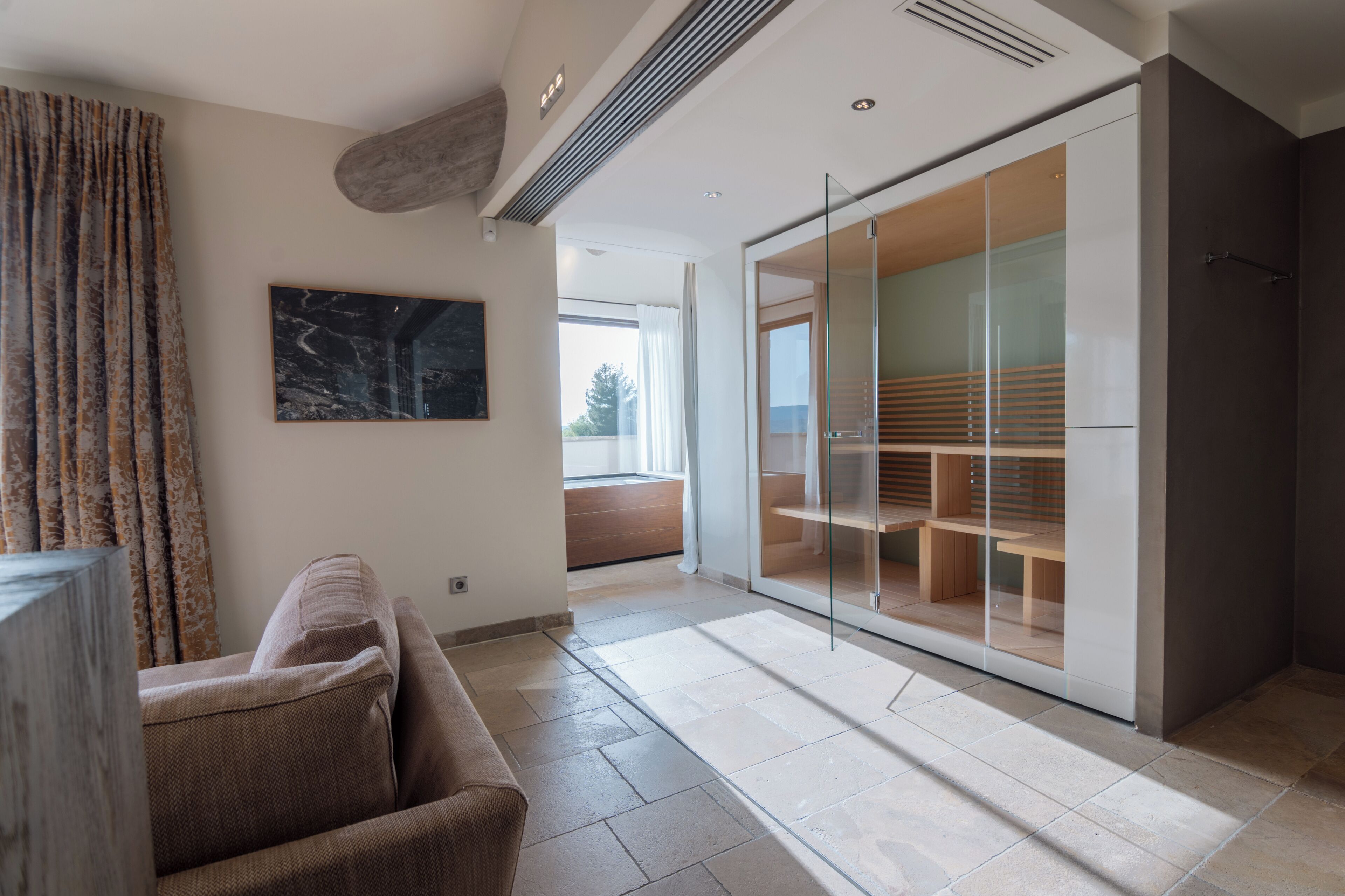 Un salon moderne avec un canapé, une cloison en verre et une vue sur l’extérieur.