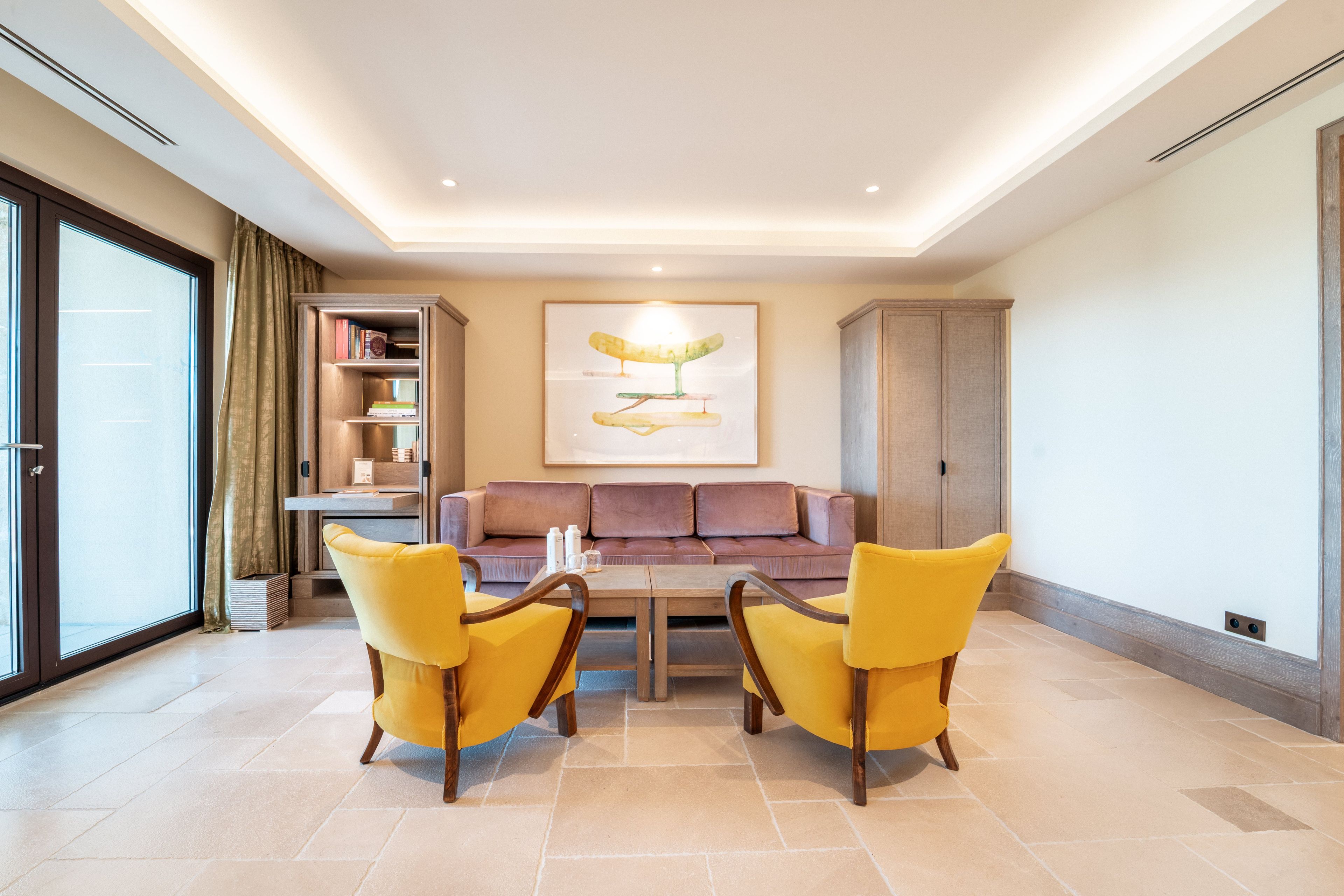 Una sala de estar con un sofá, dos sillones amarillos, una mesa de centro y una estantería.