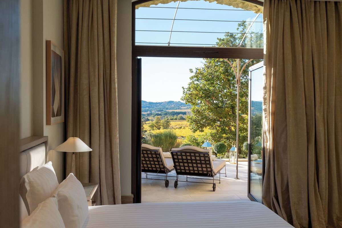 A hotel room with a large bed, a view of the outdoors, and a seating area with chairs and a table.