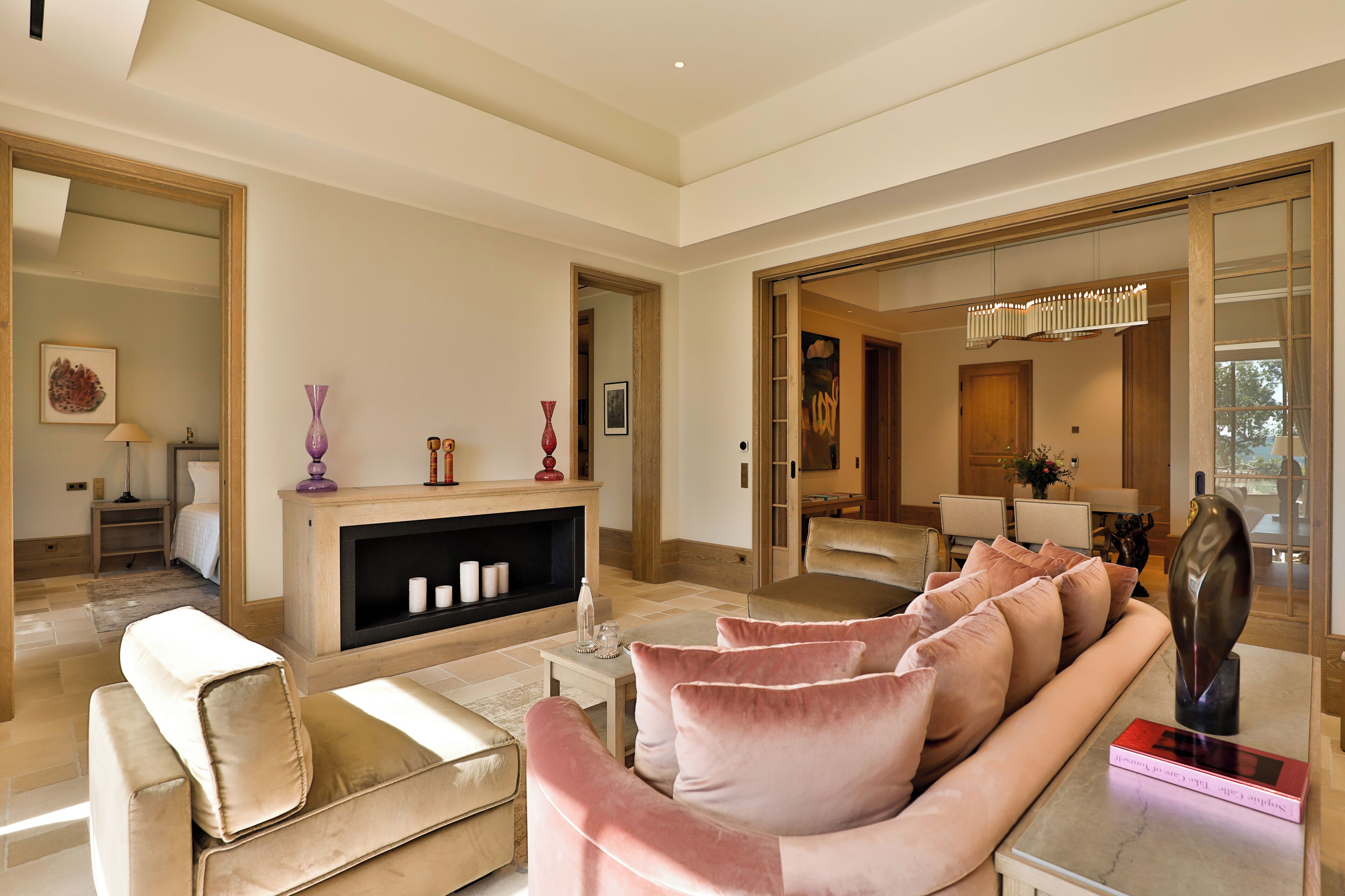 Un salon spacieux avec un canapé beige, un canapé en velours rose et une table basse en marbre.