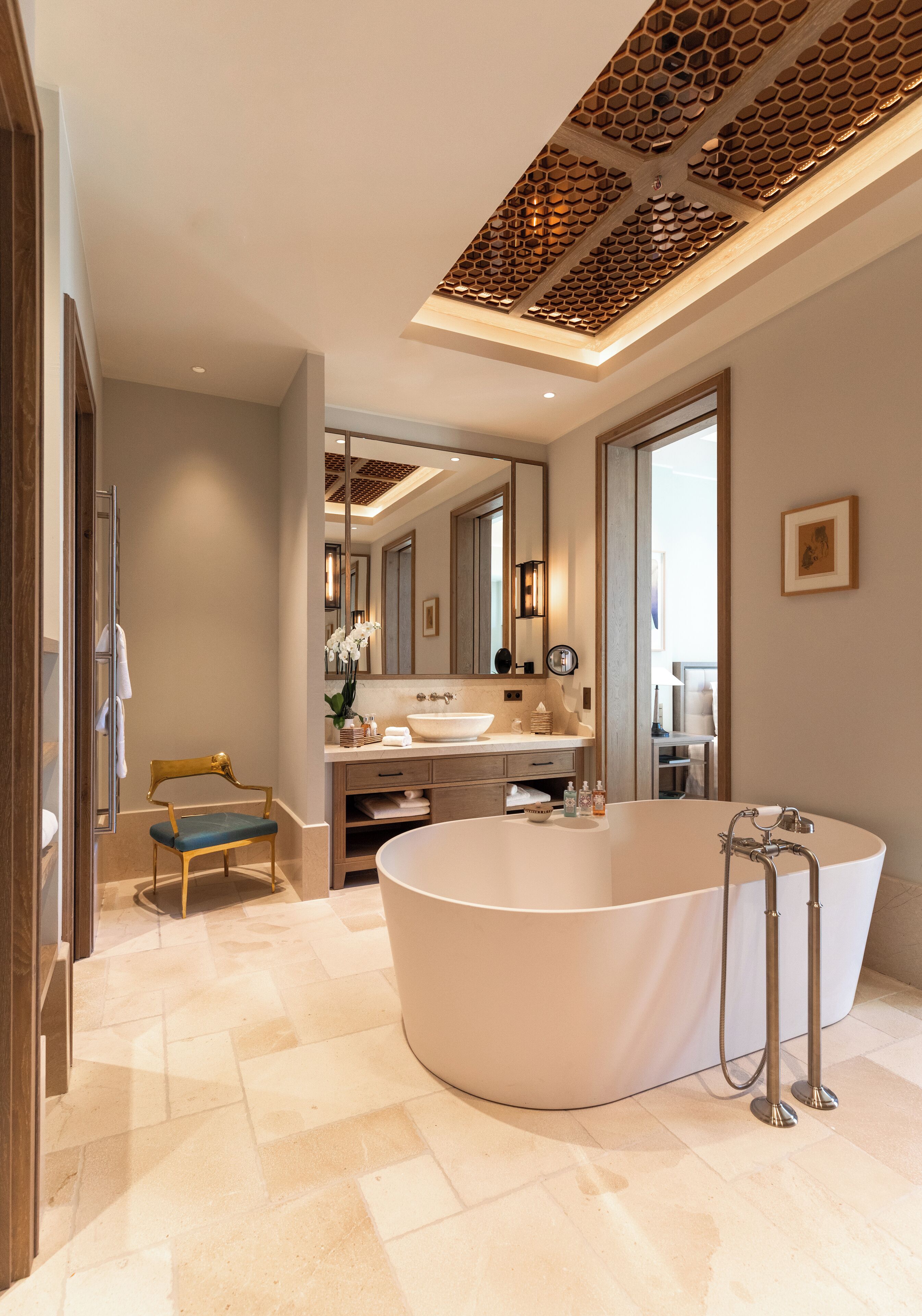 A modern bathroom with a freestanding bathtub, a vanity with a mirror, and a chair.