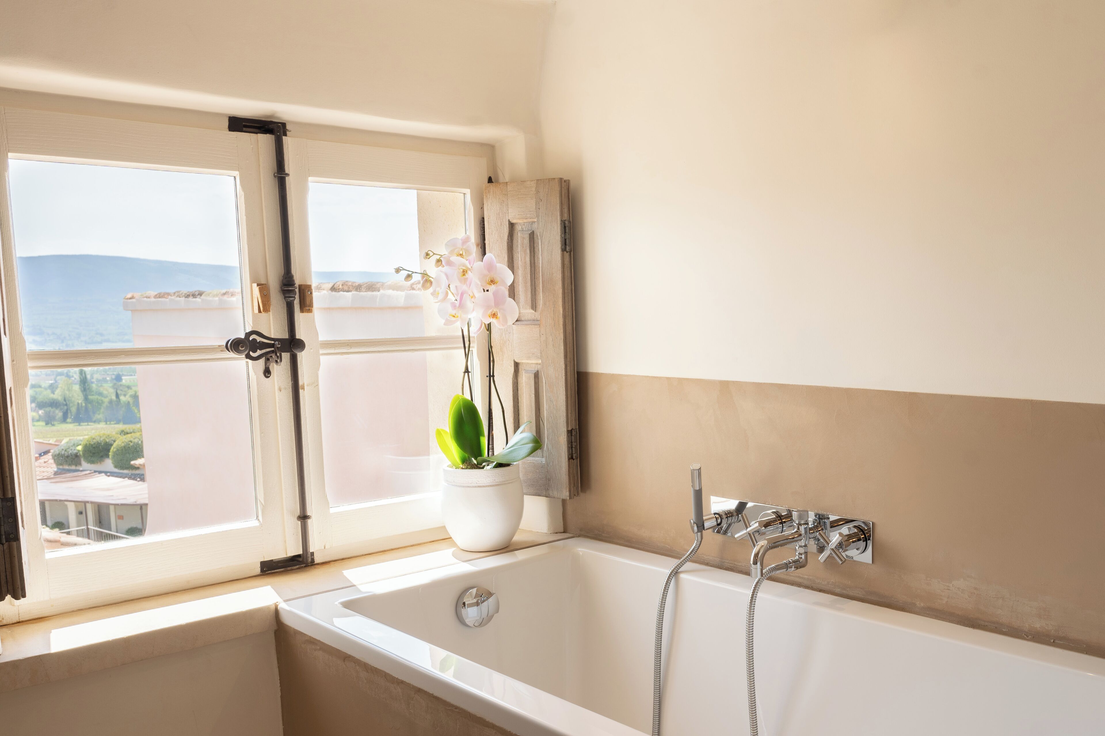 Un baño con bañera, ducha y ventana con vista al mar.