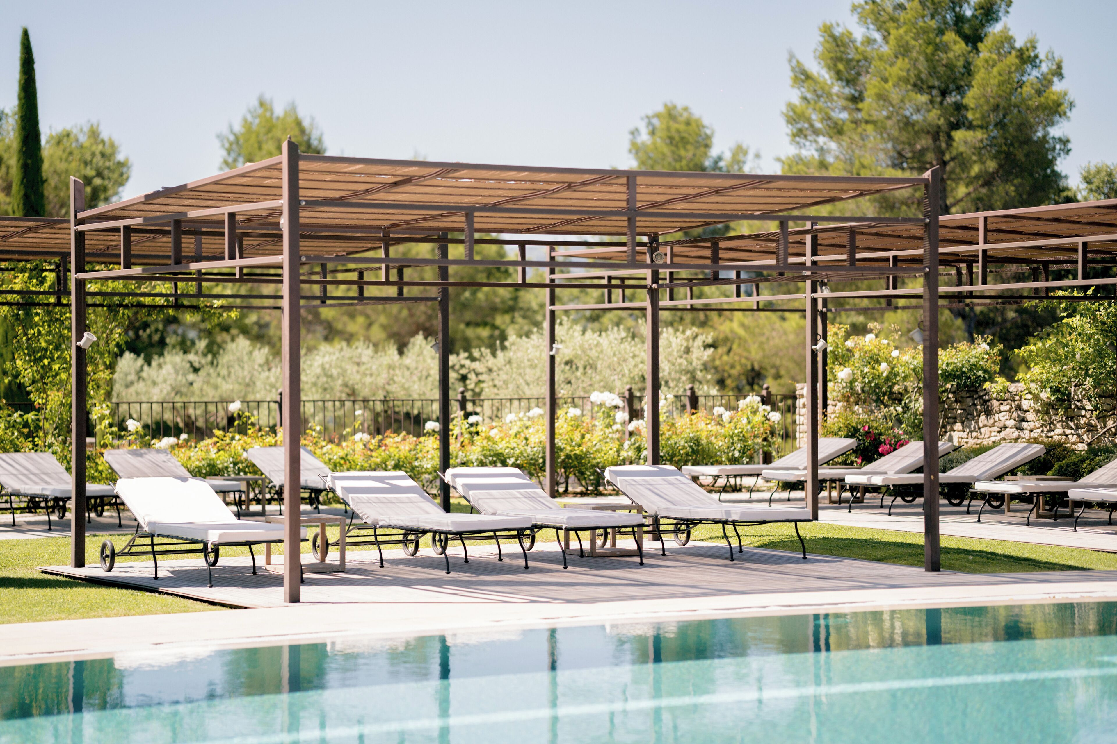 A poolside area with sun loungers and a pergola structure.