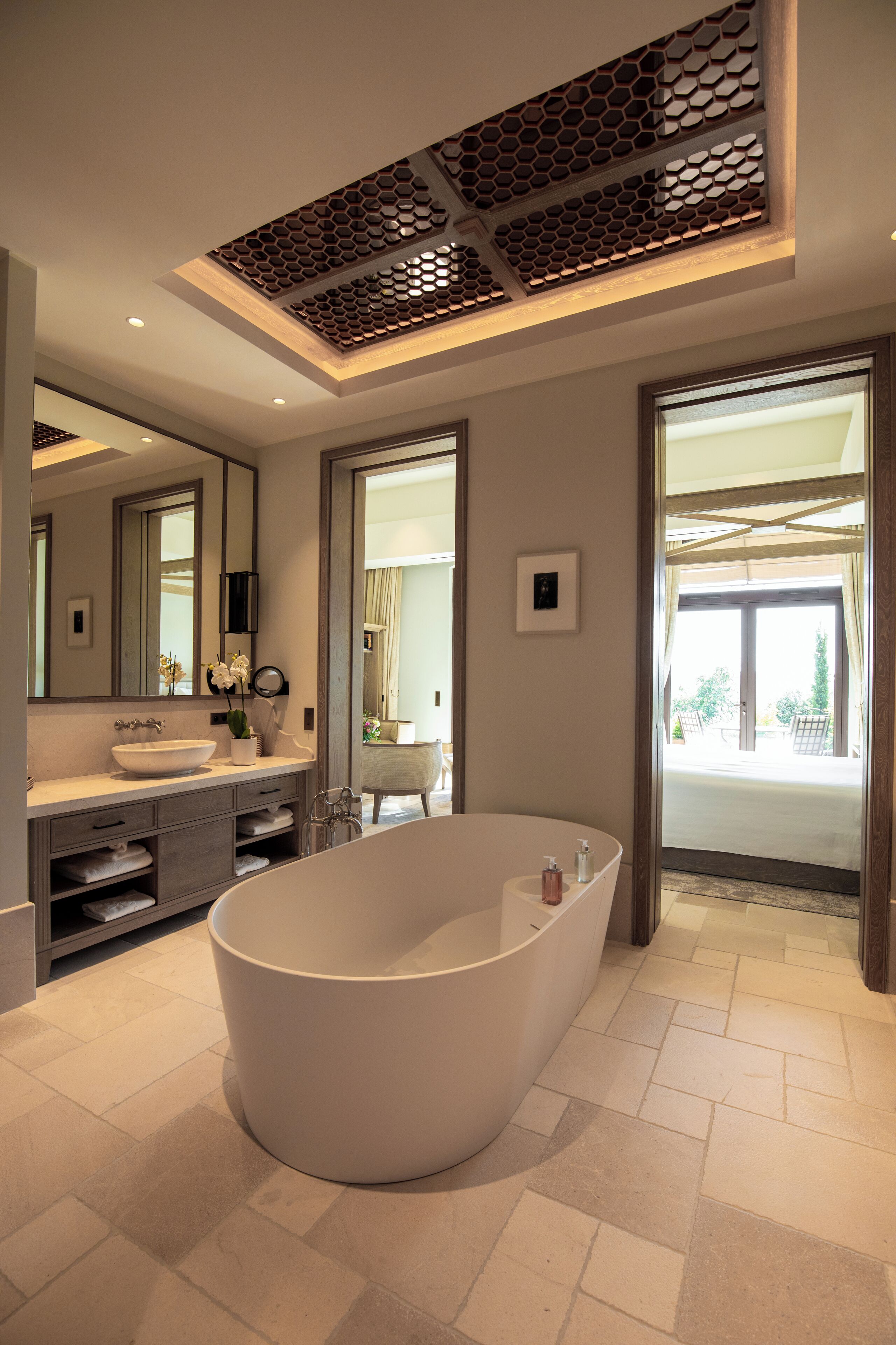 A modern bathroom with a freestanding bathtub, a large mirror, and a vanity with a sink and towel rack.