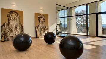 A modern interior with wooden flooring, large black spherical sculptures, and classical statues against the wall.