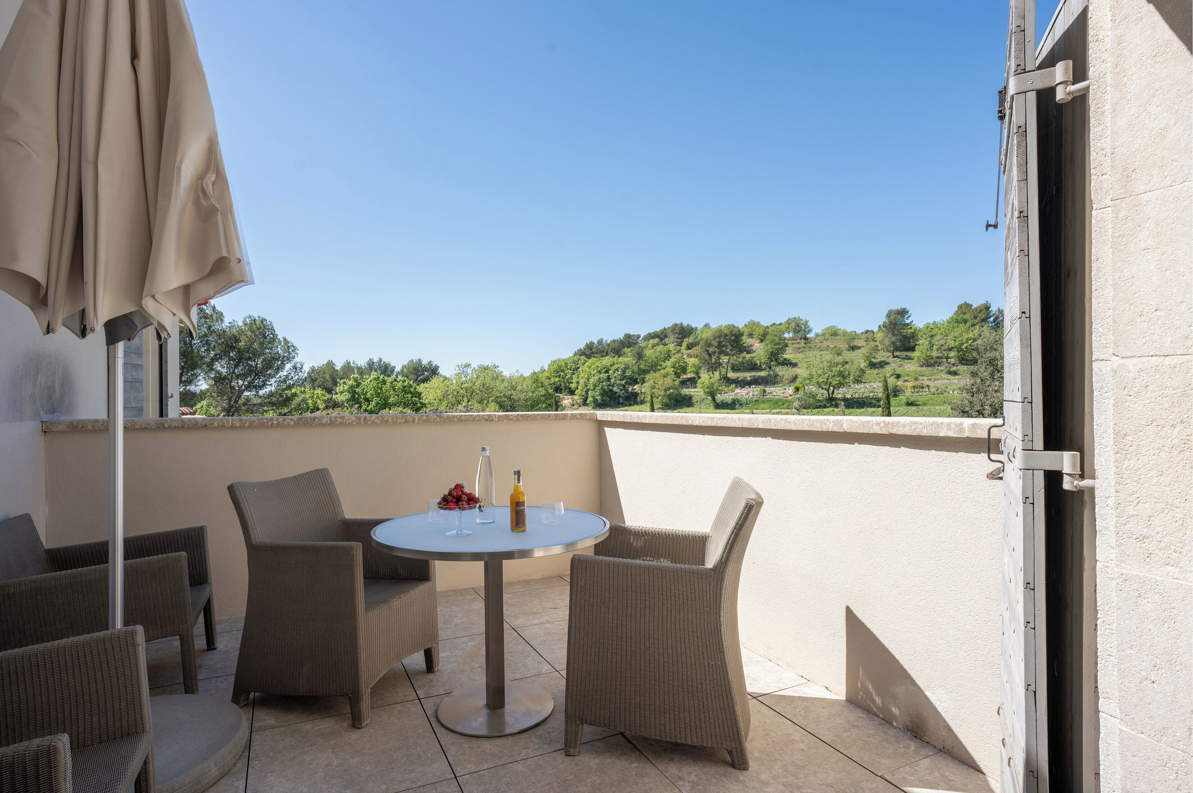 A balcony with wicker furniture, a table, and a bottle.