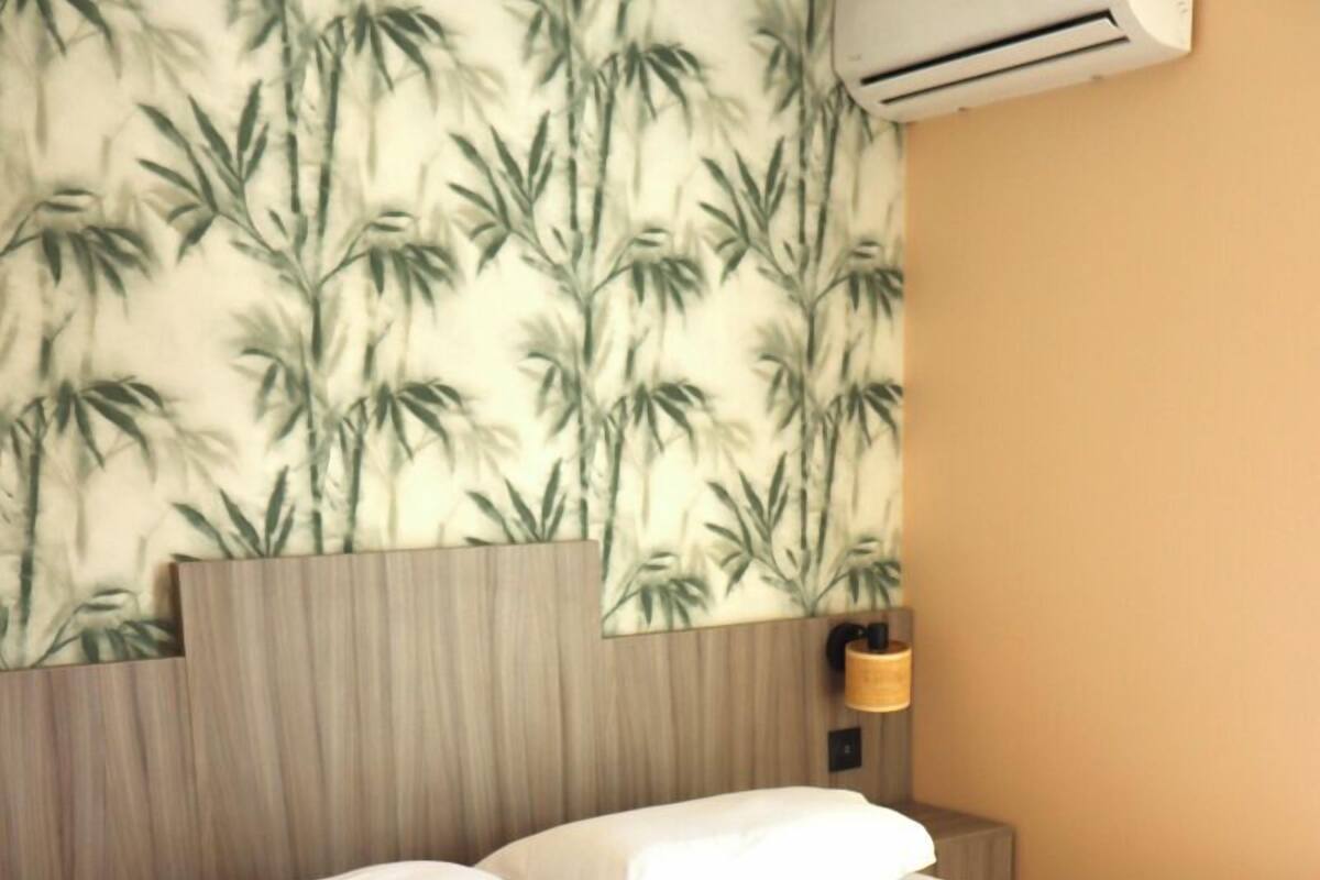 Cama bem arrumada com lençóis brancos e uma toalha dobrada ao lado.