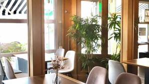 A dining area with a wooden table, cushioned chairs, and a vase with dried flowers. - Brit Hotel Essentiel Reims Taissy (Taissy)