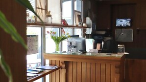 A reception area with a wooden counter, a computer, a printer, and a television on the wall. - Brit Hotel Essentiel Reims Taissy (Taissy)