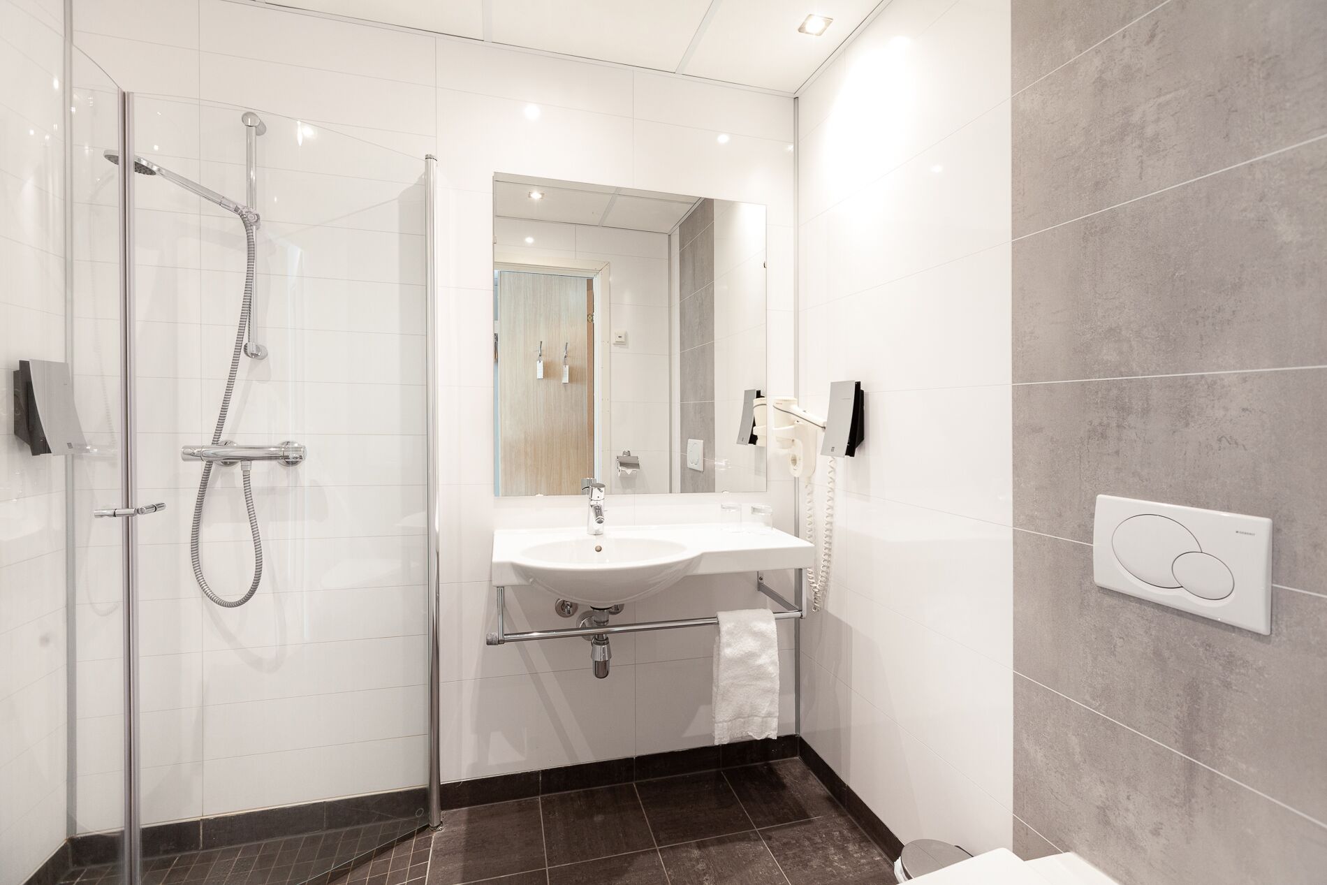 A modern bathroom with a glass-enclosed shower, a white sink, and a mirror.