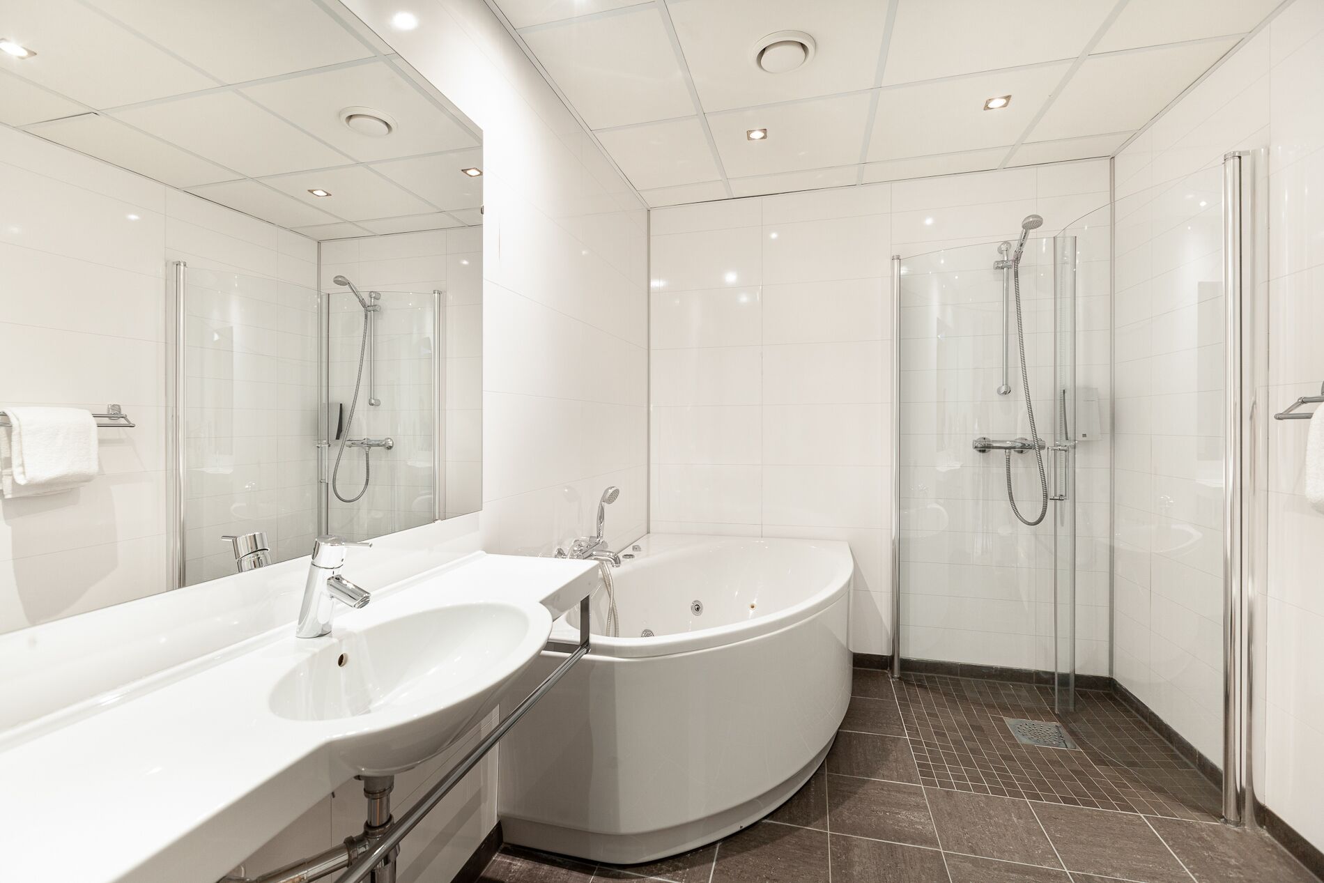 A modern bathroom with a large bathtub, a separate shower area, and a vanity with a sink.