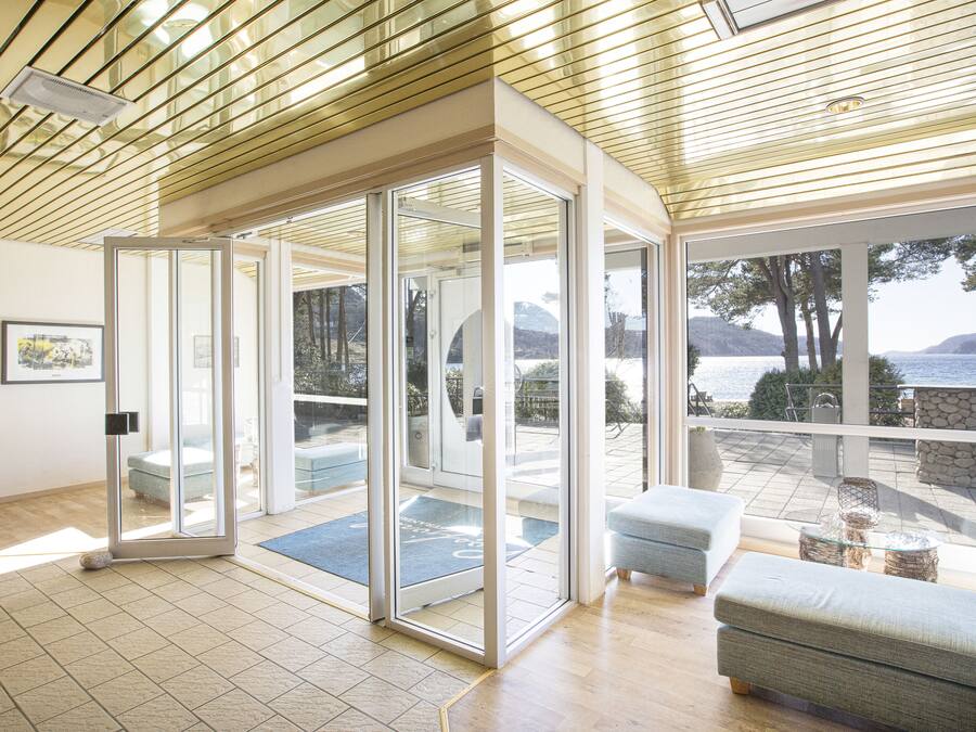 A spacious room with a large sliding glass door leading to an outdoor area with a view of the sea and mountains.