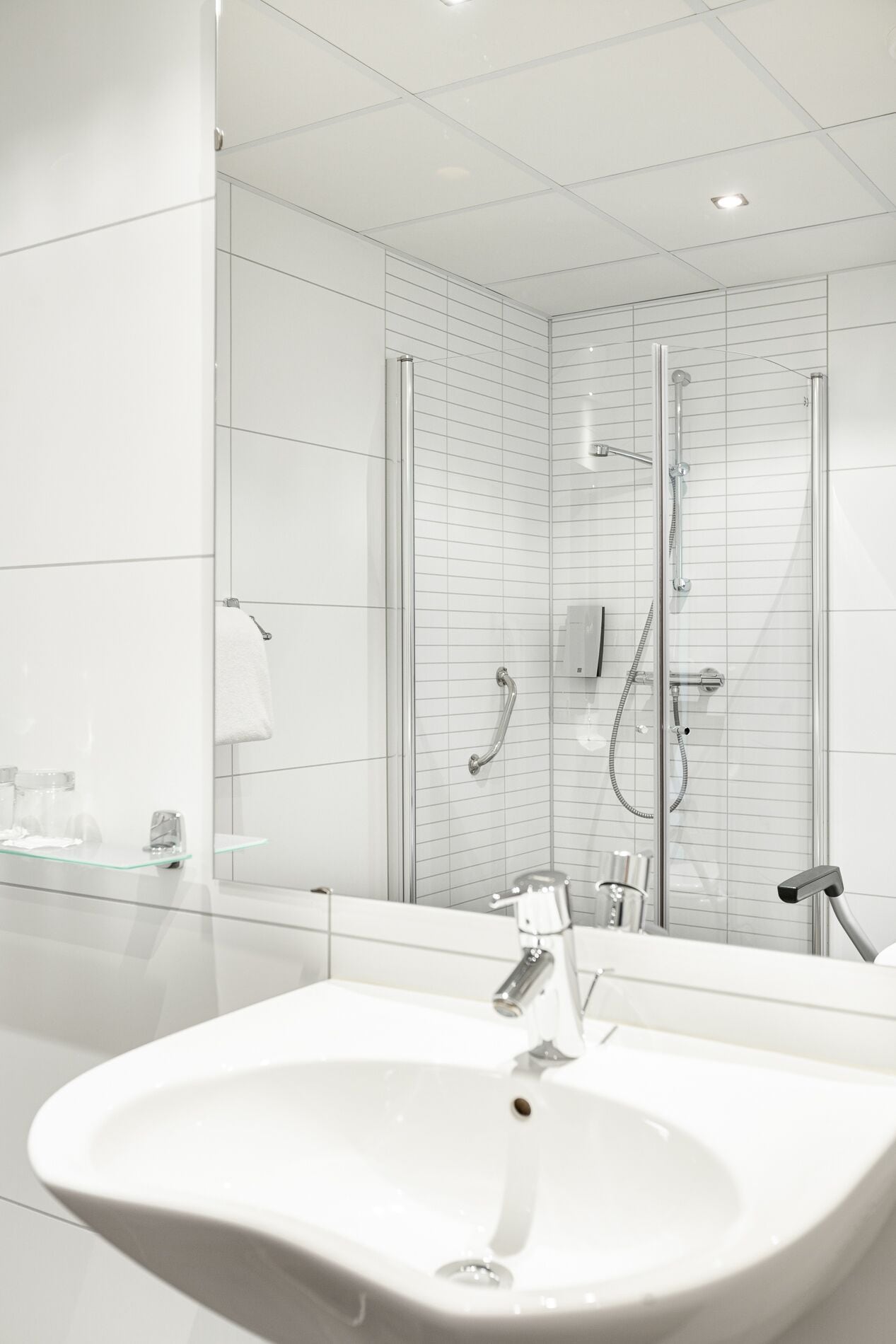 A modern bathroom with a large white sink, a glass shower enclosure, and a glass partition.