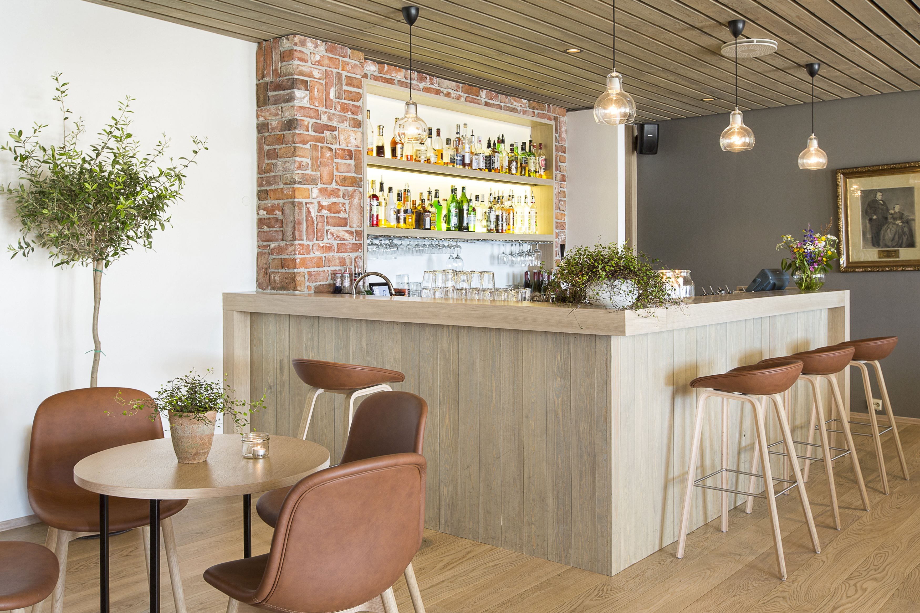 Een bar met een houten toonbank, barstoelen en een bakstenen muur.