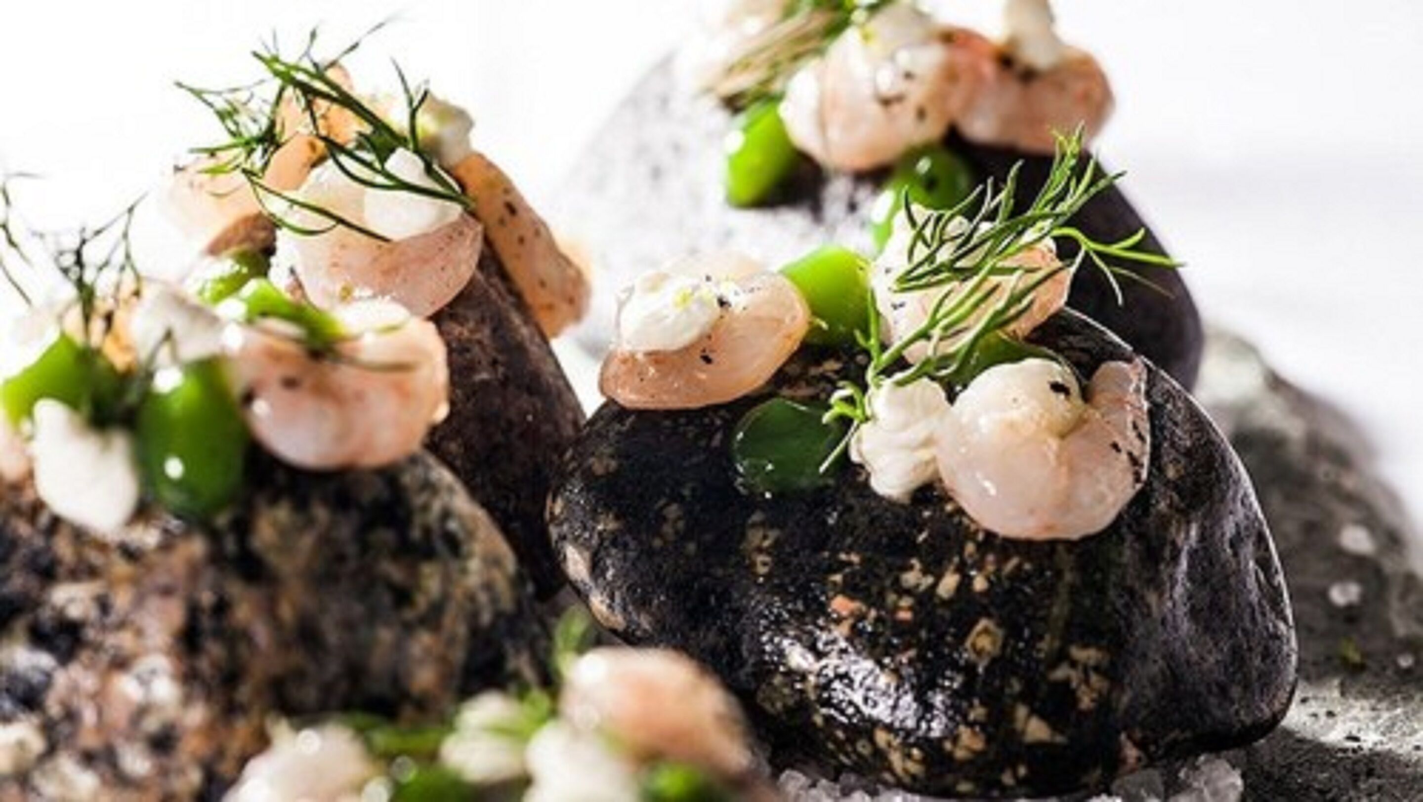 A dish with shrimp and greens on a dark, textured surface.